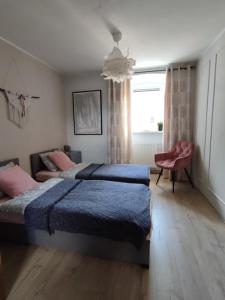 1 dormitorio con 2 camas, silla y ventana en Apartament 44, en Lądek-Zdrój