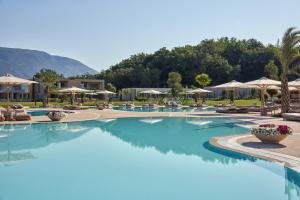 einen Pool in einem Resort mit blauem Wasser und Sonnenschirmen in der Unterkunft Ikos Odisia in Korfu-Stadt