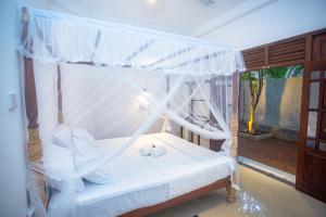 a bedroom with a canopy bed with white sheets and pillows at Kusumvillahabarduwa in Habaraduwa