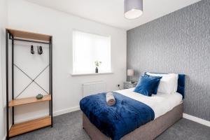 een slaapkamer met een bed met blauwe lakens en een raam bij Modern, Stylish House with Free Parking and Garden in Humberston