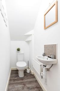 a white bathroom with a toilet and a sink at Modern, Stylish House with Free Parking and Garden in Humberston