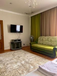 een woonkamer met een groene bank en een flatscreen-tv bij 458 Рядом Байтерек с кондиционером 2 большими кроватями и раскладным диваном для компании 1-6 человек in Astana