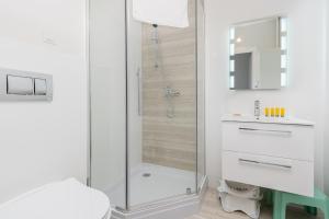 ein weißes Badezimmer mit Dusche und Waschbecken in der Unterkunft Osiedle Kombatantów Standard Apartment in Krakau + 20 Fotos
