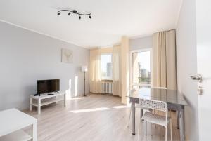 ein weißes Wohnzimmer mit einem Tisch und einem TV in der Unterkunft Osiedle Kombatantów Standard Apartment in Krakau