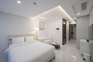 biała sypialnia z białym łóżkiem i telewizorem w obiekcie Zizel Raonjae 2 w Seulu