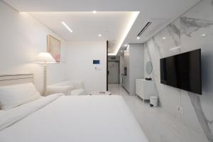 a white bedroom with a large bed and a tv at Zizel Raonjae 2 in Seoul