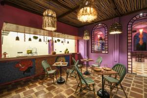 een restaurant met paarse muren en stoelen en tafels bij El Barrio Boutique Hotel & Bar in Canggu