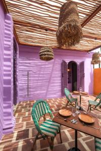 een kamer met een tafel en stoelen en paarse muren bij El Barrio Boutique Hotel & Bar in Canggu