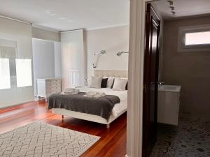 a white bedroom with a bed and a bathroom at Apartxibi in Bermeo