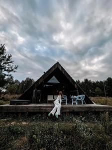 een vrouw zit op een veranda van een huis bij Aušrinės in Liškiava