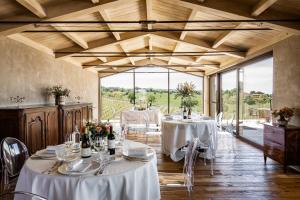 un comedor con mesas y sillas blancas y ventanas en Country House Oliveto sul Lago, en San Nicolò