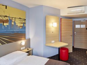 ein Hotelzimmer mit einem Bett und einem Schreibtisch in der Unterkunft B&B Hotel Saarbrücken-Hbf in Saarbrücken