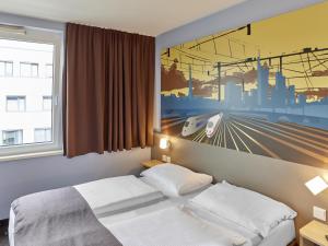 a bedroom with a bed and a painting on the wall at B&B Hotel Saarbrücken-Hbf in Saarbrücken