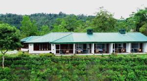 a large white house with a green roof at Kobbekaduwa Bungalow in Kandy