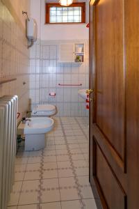 een badkamer met 2 toiletten, een wastafel en een deur bij Orsini: tre camere da letto, 2 bagni in Luco neʼ Marsi