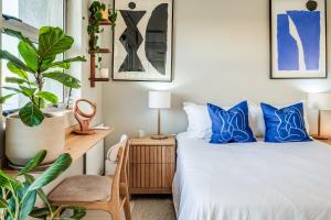 a bedroom with a bed with blue pillows and a plant at The Apartment in Mouille Point in Cape Town