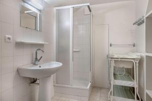 La salle de bains blanche est pourvue d'un lavabo et d'une douche. dans l'établissement Escapade conviviale et familiale pres de la plage, à Pornichet