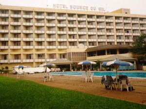 un hotel con piscina, sedie e ombrelloni di Hôtel Source Du Nil a Bujumbura