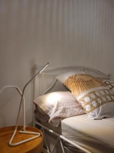 una cama con una lámpara junto a una almohada en Appartement avec grand jardin reposant en Le Mans