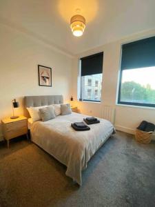 a bedroom with a large bed and two windows at Beautiful 1 Bed Flat near NEC with secure parking in Birmingham