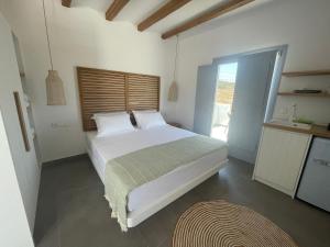斯希努薩島的住宿－Sohoros Luxury Suites，卧室配有一张白色大床和木制床头板