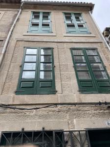 tre finestre su un edificio con persiane verdi di Casa Arco a Pontevedra