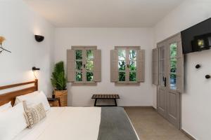 1 dormitorio con 1 cama blanca grande y ventanas en Marillia Village en Perivolos