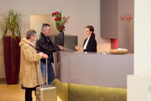 a man and a woman standing at a counter with a suitcase at Hotel Staffler in Odelzhausen