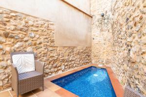 a swimming pool with a chair next to a stone wall at Casa Romana in Pollença