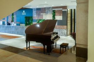 a brown piano in a lobby with a stool at Hotel Royal Signature in Kuala Lumpur