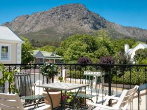 a table and chairs on a balcony with a mountain at Le Petit Paris in Franschhoek
