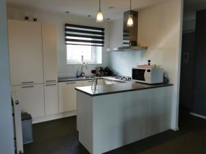 cocina blanca con fregadero y microondas en Housing De Brouwerij, en Westdorpe