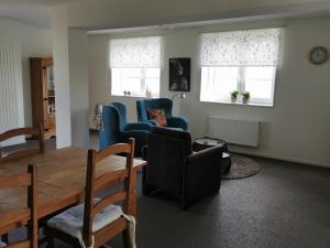 ein Wohnzimmer mit Stühlen, einem Tisch und Fenstern in der Unterkunft Housing De Brouwerij in Westdorpe