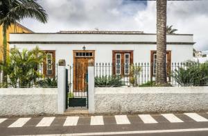 una casa blanca con una puerta y una palmera en Donde Conchita, buhardilla con baño compartido, cerca del aeropuerto norte en La Laguna