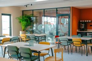 un comedor con mesas, sillas y ventanas en Kyriad Marseille Palais Des Congrès – Vélodrome, en Marsella