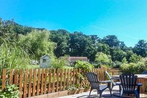 2 sillas y una mesa en un jardín con una valla en Superbe gîte pour 15 personnes, en Le Ménil-Brout