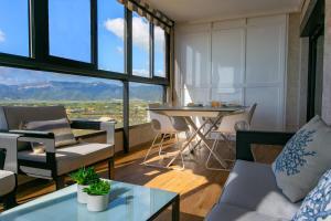 a living room with a table and chairs and windows at Cullera Beach Apartment Espacio in Cullera
