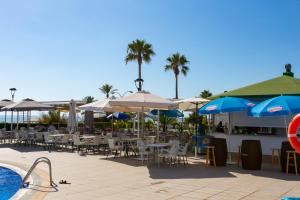 a swimming pool with tables and chairs and umbrellas at Cullera Beach Apartment Espacio in Cullera