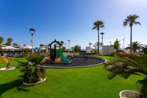 a playground with a slide in a park with palm trees at Cullera Beach Apartment Espacio in Cullera