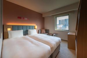 広島市にあるザ ロイヤルパークホテル 広島 リバーサイドの窓付きの客室で、白い大型ベッド1台が備わります。