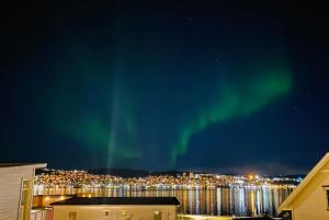 Un'immagine dell'aurora nel cielo sopra una città di Polar Cozy Apartment - Free parking a Tromsø