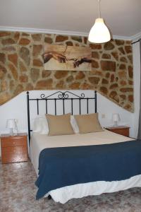 a bedroom with a large bed and a stone wall at Casa La Azotea de Cazorla in Cazorla