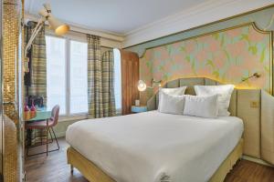 una camera da letto con un grande letto bianco con un muro di Idol Hotel a Parigi