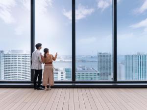 a couple standing in front of a window looking at the city at Mitsui Garden Hotel Yokohama Minatomirai Premier in Yokohama