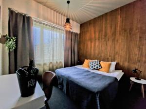 a bedroom with a bed with blue sheets and a window at Hotel Seurahuone Riihimäki in Riihimäki