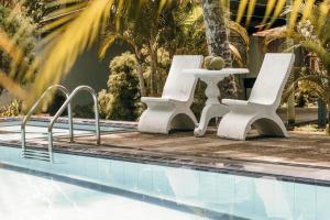 two white chairs and a table next to a swimming pool at Villa Elegance in Galle