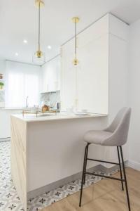 a white kitchen with a chair and a counter at Exclusiva vivienda en la Calle Jorge Juan in Madrid