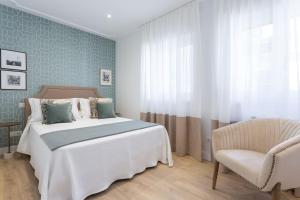 sypialnia z dużym łóżkiem i krzesłem w obiekcie Exclusiva vivienda en la Calle Jorge Juan w Madrycie