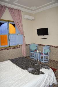 - une chambre avec un lit, 2 chaises et une télévision à écran plat dans l'établissement villa atika, à Marrakech