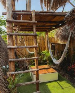 a hammock in a tropical garden with a fence at Macarena Paredon in El Paredón Buena Vista